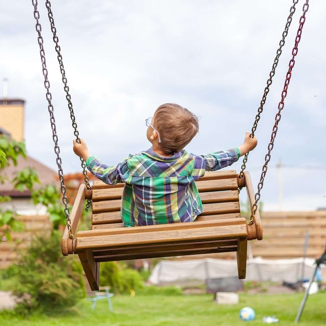 Child swinging on swing in the backyard
