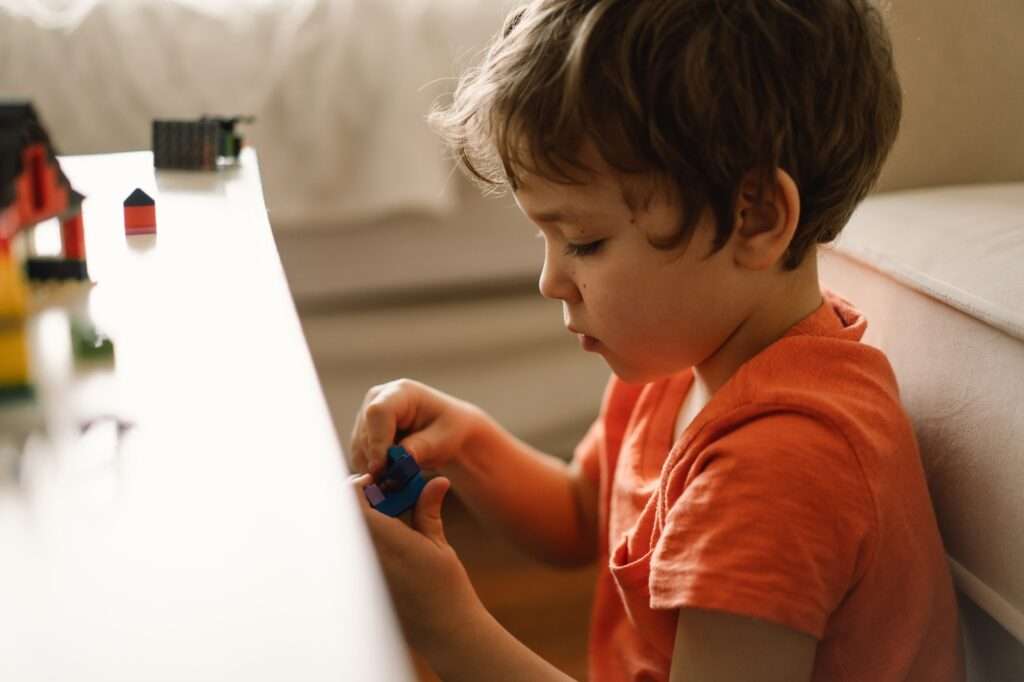 Cute boy is playing constructor at home. Kid playing block toys in home at nursery.